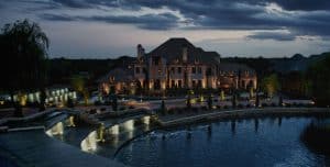 A mansion's lighting seen from the outskirts of the grounds