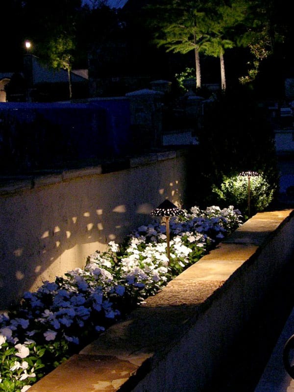 A decorative shade creates a pattern shadow over a flower garden