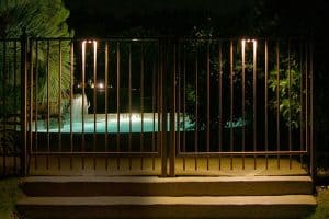 Light shining on a waterfall flowing into a pool can be seen through a fence