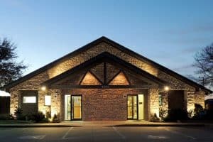 The entrance to a stone clinic building is lit byy security lighting at night