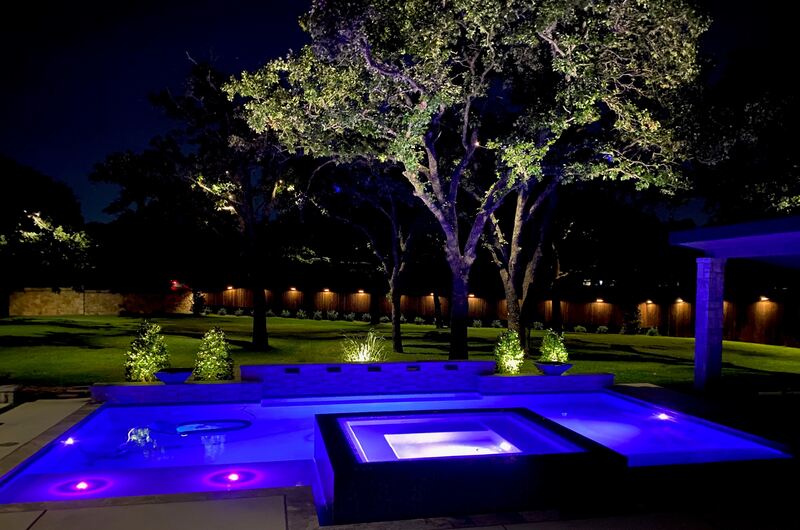 a pool lit up blue surrounded by outdoor lighting