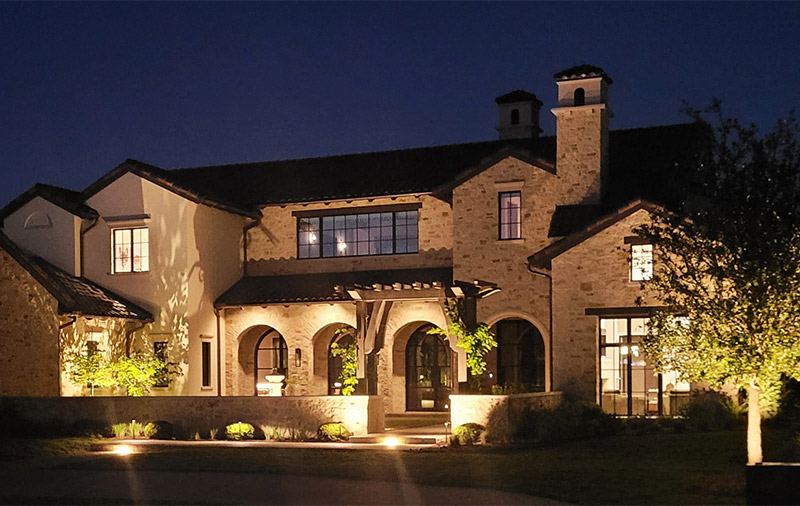 stone style home lit up with out door lighting